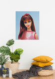 Twist 'N Turn Barbie oil painting by Judy Ragagli hangs on a wall above yellow pillows and a plant.